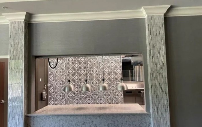 A modern kitchen interior featuring patterned tiles and sleek pendant lights over a countertop.