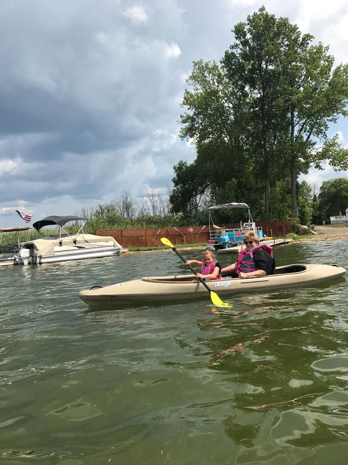 A group of people kayaking on a lake surrounded by trees and other boats.