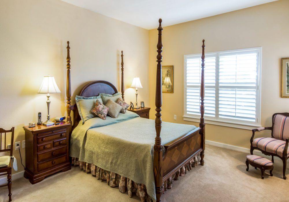 A cozy bedroom featuring a four-poster bed and two nightstands with lamps.