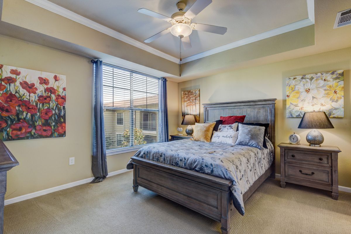 A cozy bedroom with a large bed, ceiling fan, and a window with curtains.
