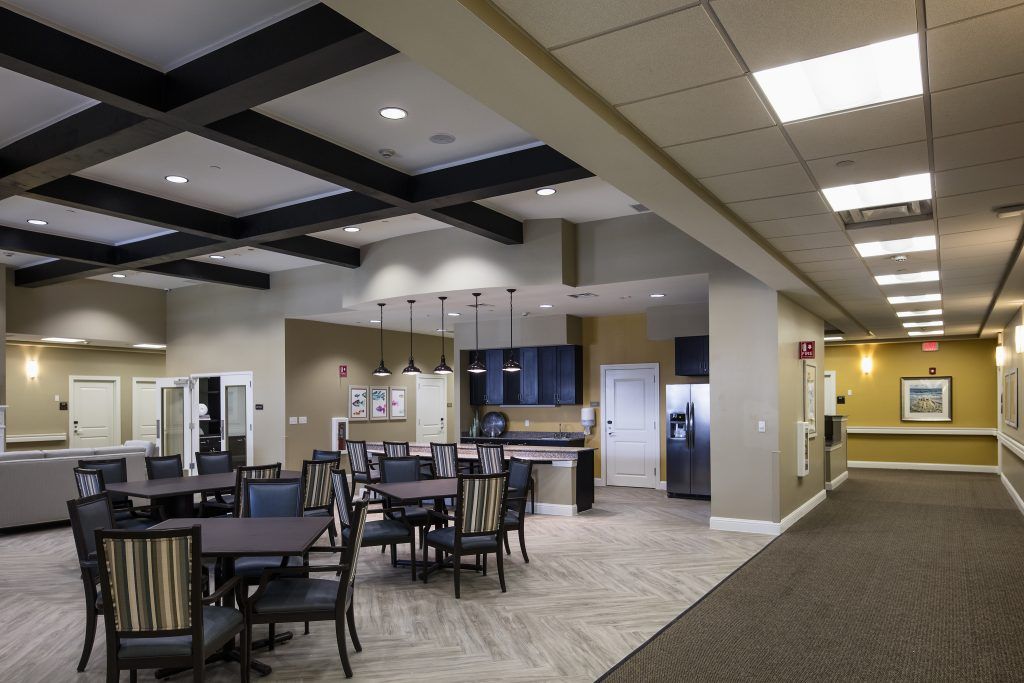 A modern dining and kitchen area featuring several tables and chairs with contemporary lighting.