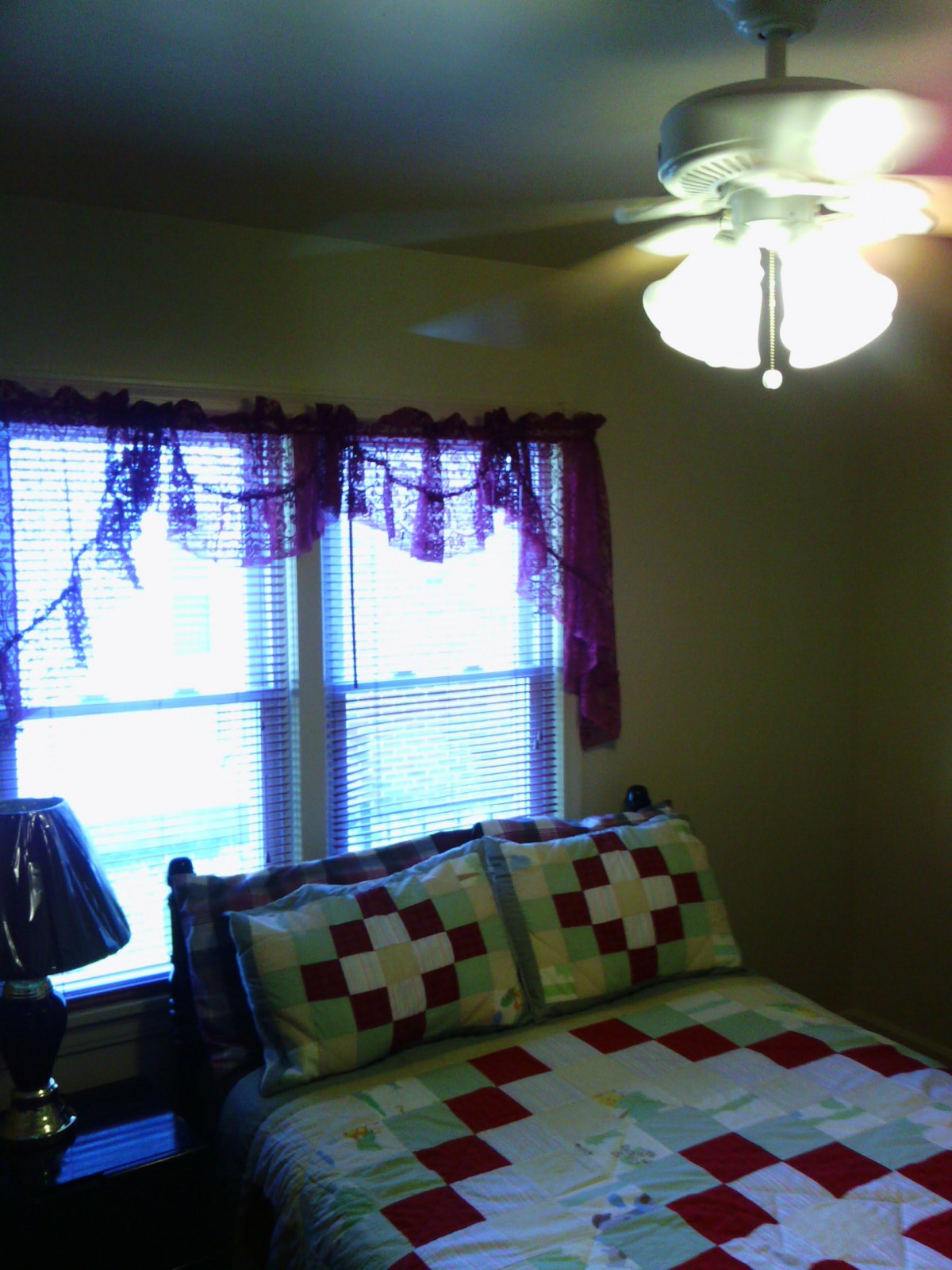 A cozy bedroom with a quilted bedspread and decorative curtains.