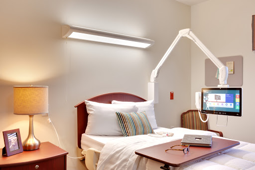 A well-lit hospital room featuring a neatly made bed and medical equipment.