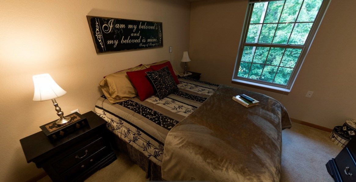 Cozy bedroom with a neatly made bed, decorative pillows, and soft lighting.