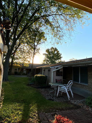 A serene evening scene in a residential area, with trees and patio chairs basking in the warm glow of the setting sun.