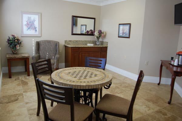 A cozy dining area with a round table and four chairs, complemented by a mirror and artwork on the walls.