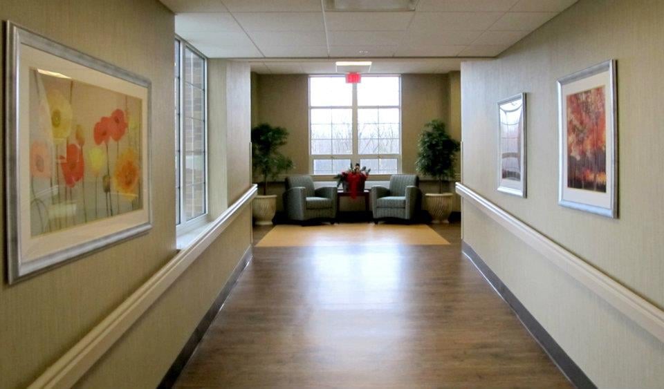 A quiet hallway with a seating area by the window, featuring two armchairs and decorative plants.