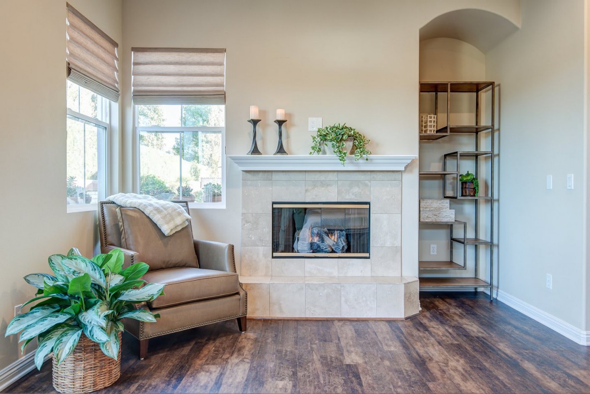 A cozy living room featuring a fireplace, armchair, and hardwood flooring.