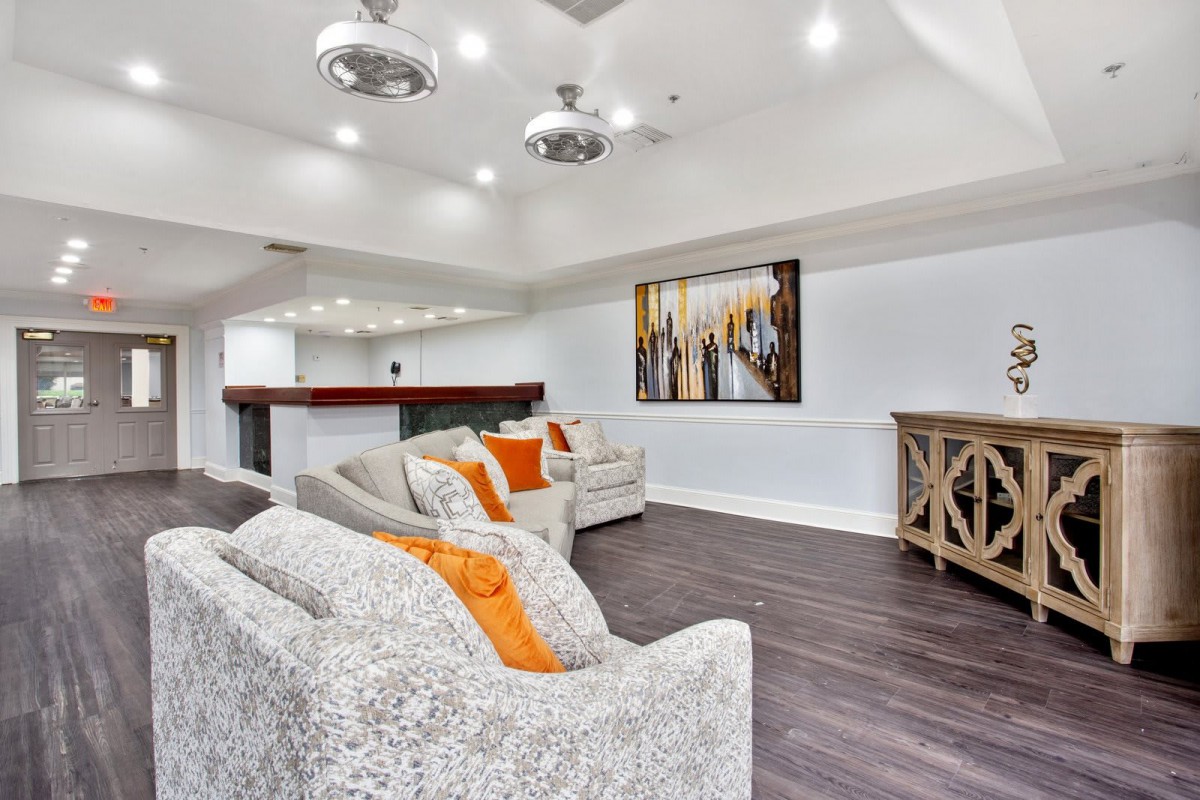 A modern living room with stylish decor, featuring a comfortable sofa, vibrant artwork, and sleek wood flooring.