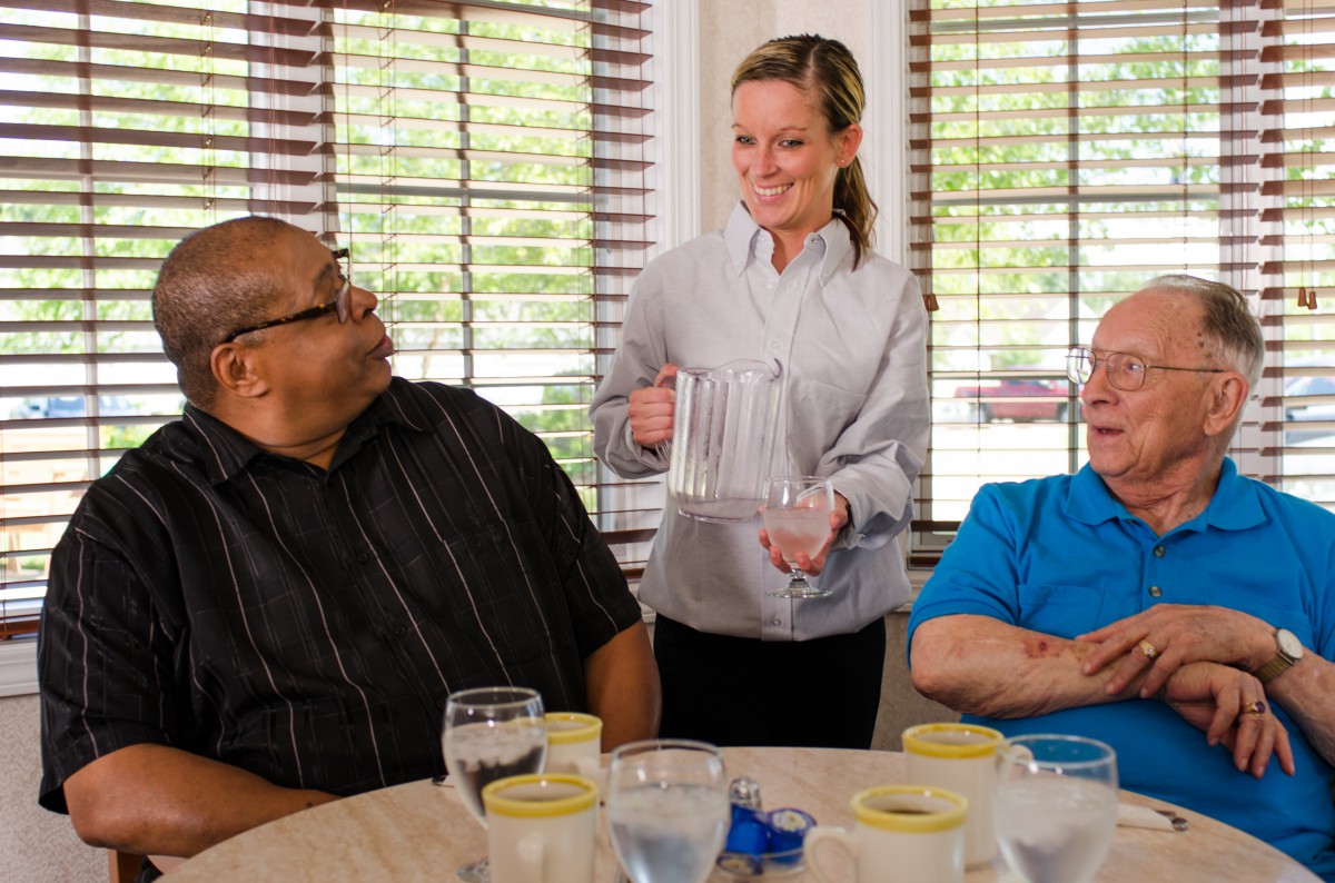 A server pours water for guests at a dining table.