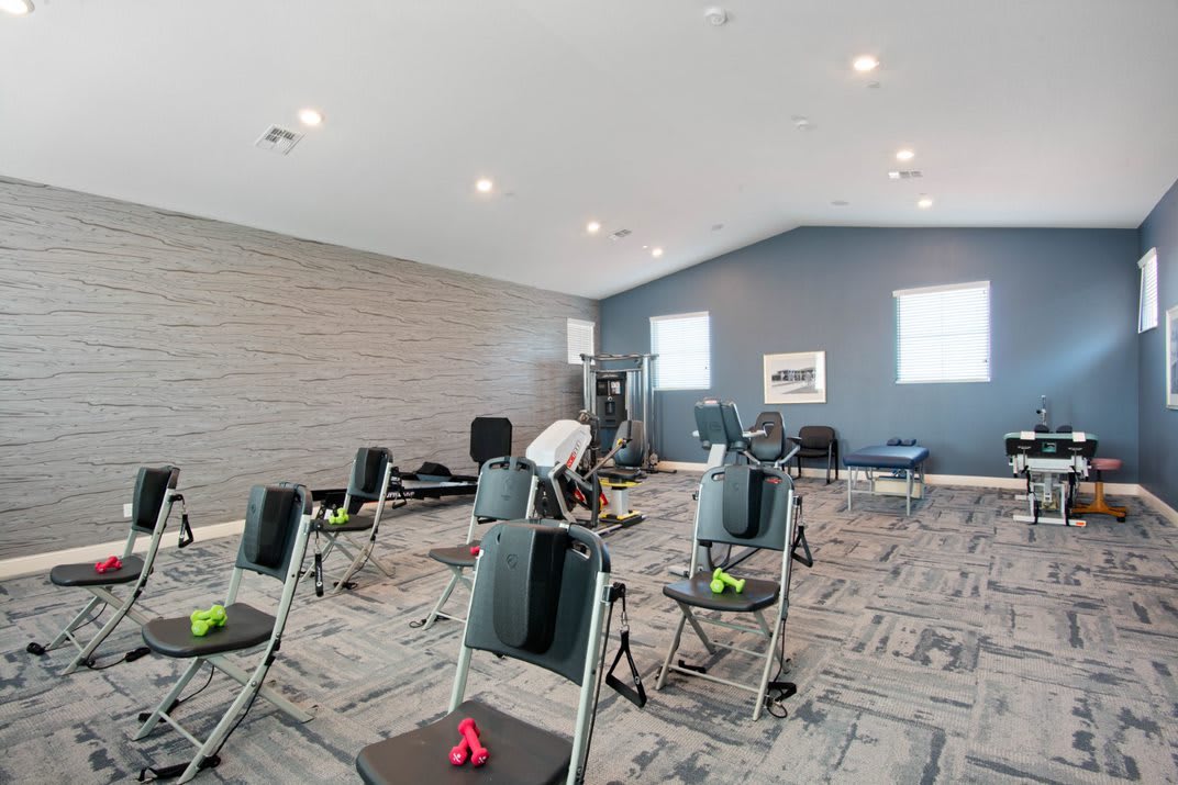 A well-lit exercise room with chairs and dumbbells arranged for a fitness class.