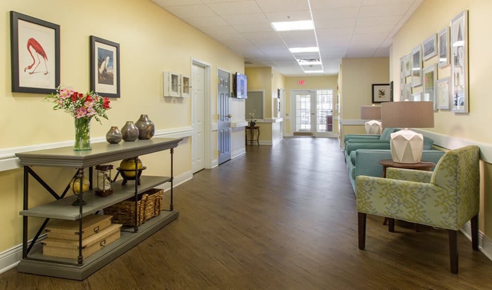 A well-lit hallway with wooden flooring, decorated with furniture and decorative items.
