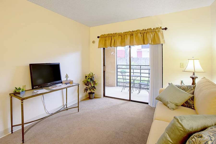 A cozy living room with a television, sofa, and access to a balcony.