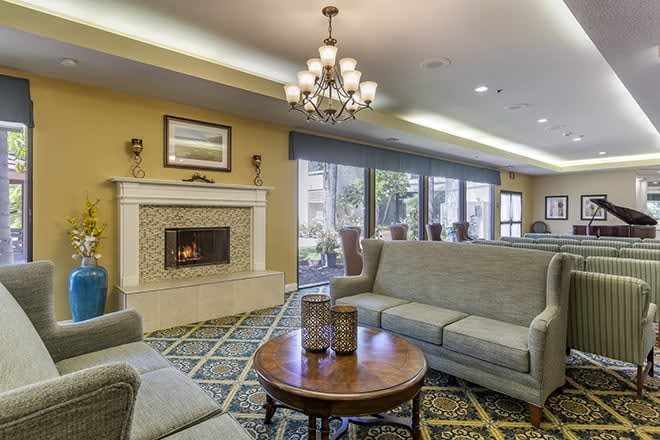 A cozy living room with sofas, a coffee table, and a fireplace under a chandelier.