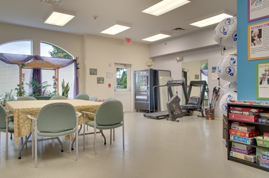 A multi-purpose room featuring gym equipment, seating area, and a vending machine.