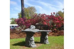 Stone table and chairs set in a garden surrounded by vibrant foliage.
