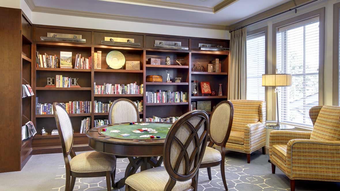 A cozy library room with bookshelves, a round table, and comfortable seating.