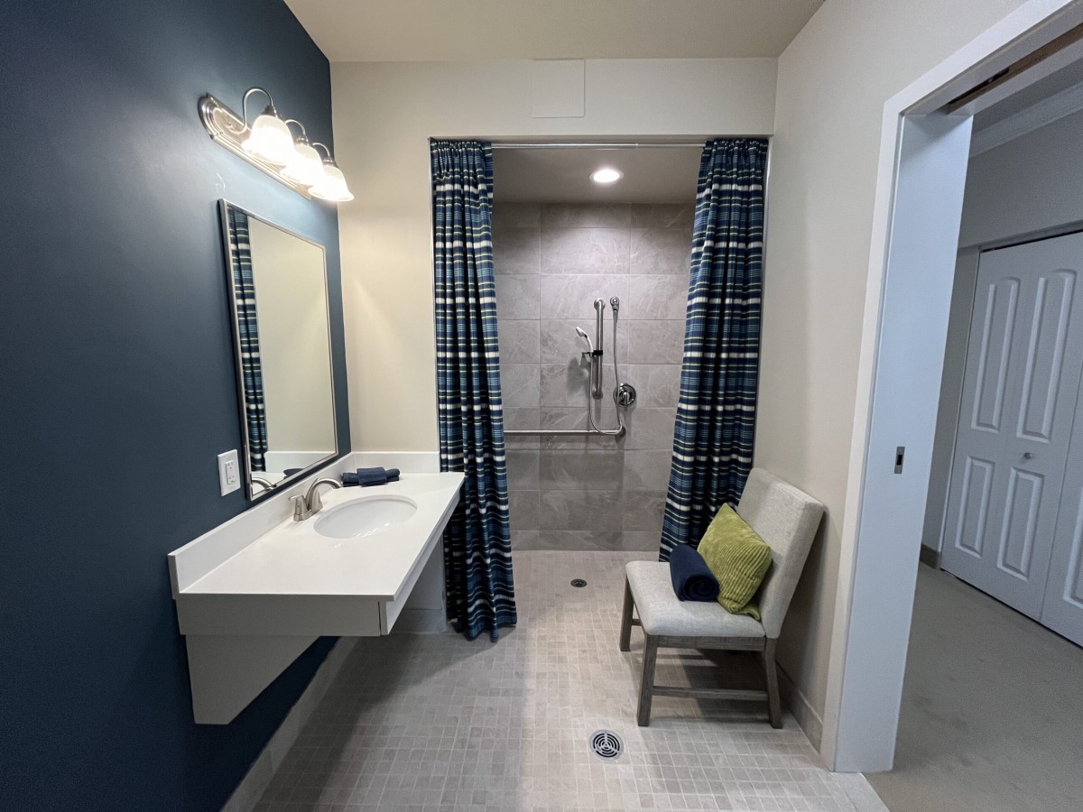 A modern bathroom with a walk-in shower, plaid curtains, and a minimalistic design.