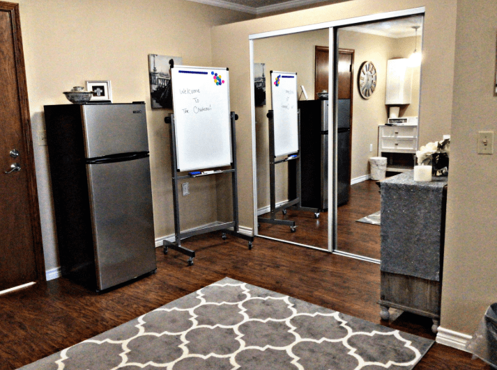 Office space with a whiteboard, refrigerator, and mirrored closet.