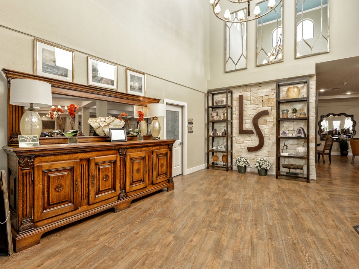 A welcoming entryway featuring elegant wooden furniture, decorative shelves, and a chandelier.