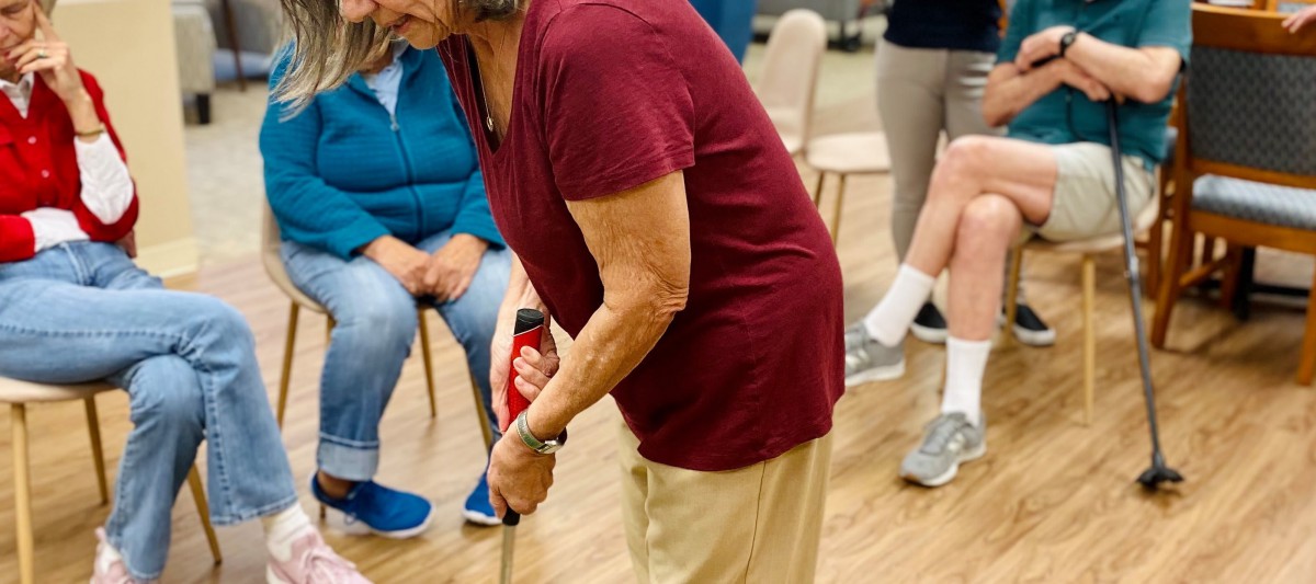 An elderly person participates in a group exercise or physical therapy session indoors.