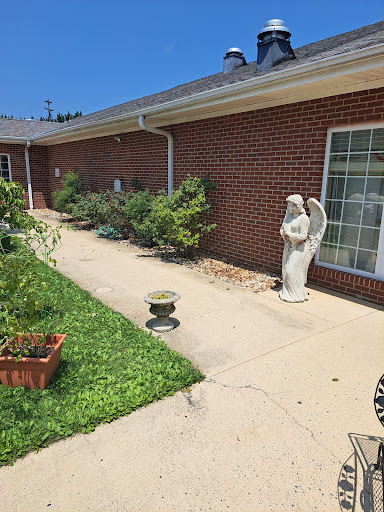 A serene garden pathway lined with greenery and a decorative angel statue.