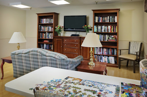 A cozy living room featuring a sofa, bookshelves filled with books, a television, and a table with a jigsaw puzzle.