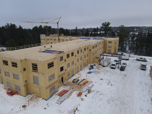 A winter construction site featuring a partially built wooden structure surrounded by snow.