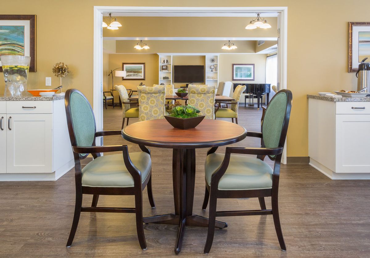 A cozy dining area with a wooden table, two upholstered chairs, and a decorative plant centerpiece.