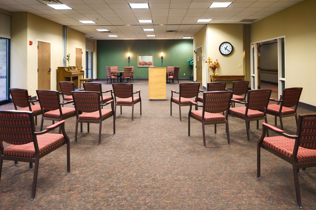 An empty conference room with arranged chairs and a podium at the front.