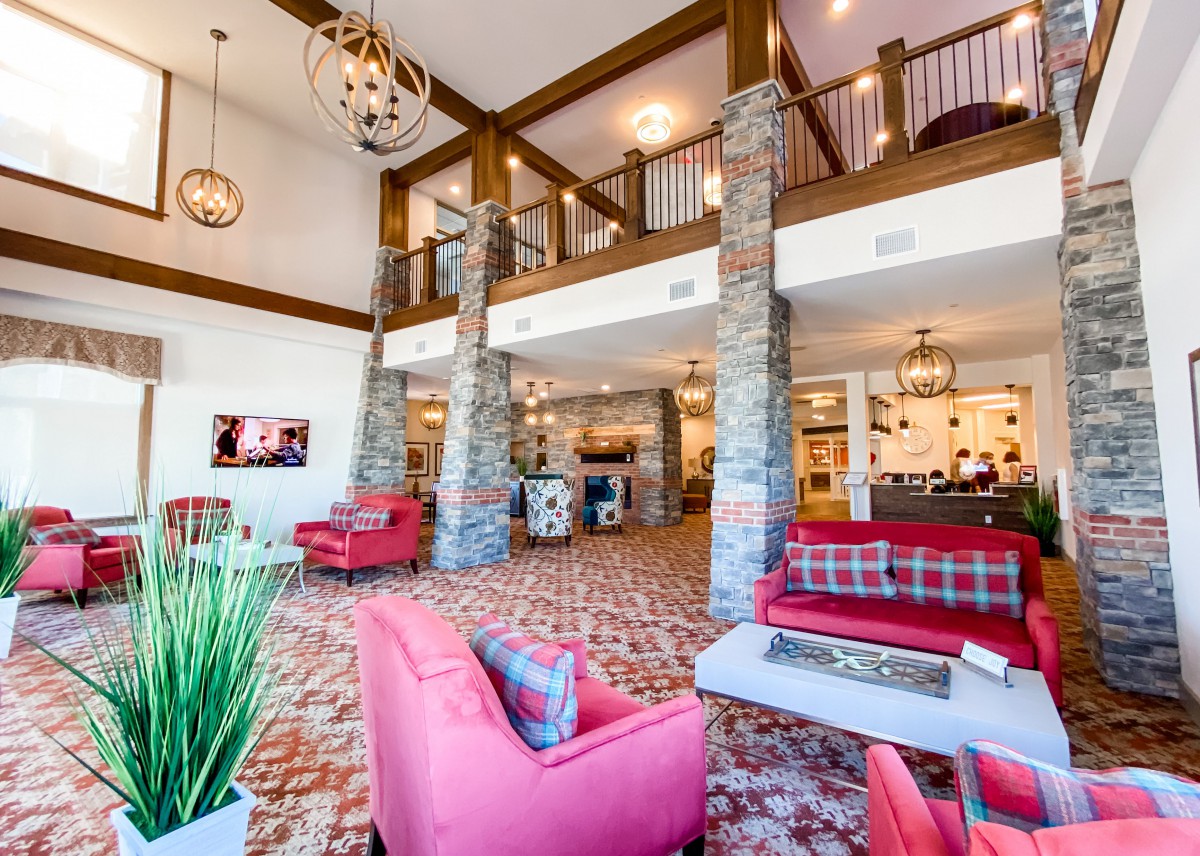A modern and spacious hotel lobby with red sofas and stone columns.
