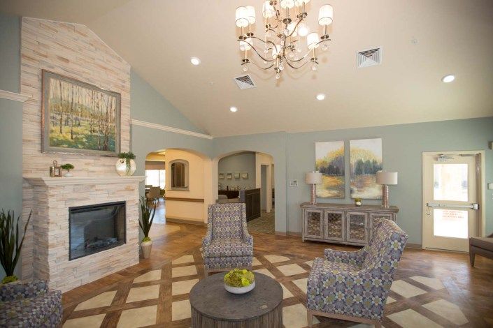 A modern living room featuring a chandelier, fireplace, and stylish furniture.