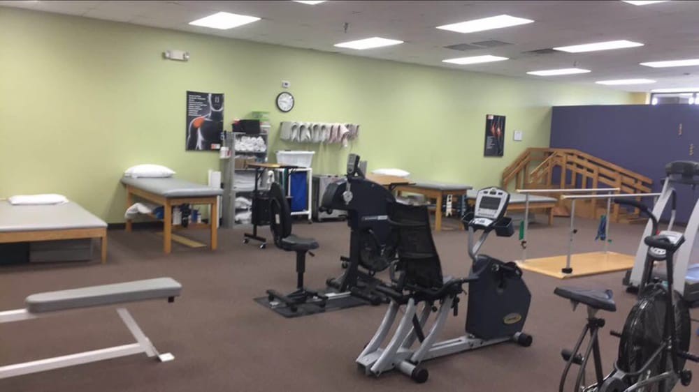 A rehabilitation center with exercise equipment and therapy tables.