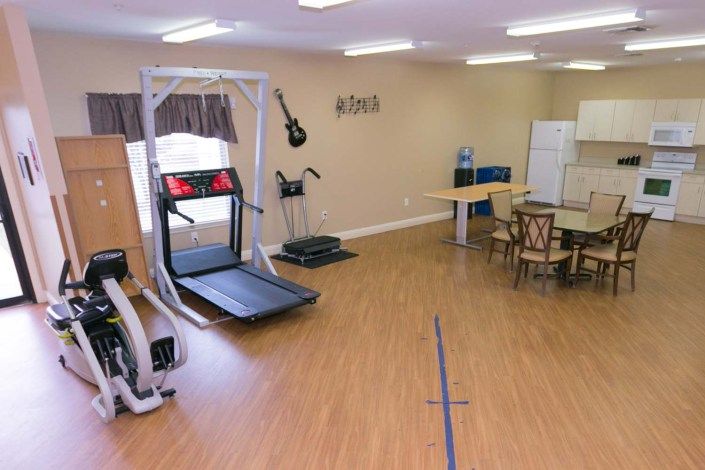 A rehabilitation room featuring a treadmill and other exercise equipment on a wooden floor.