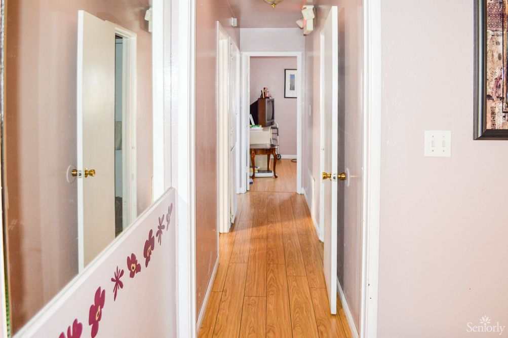 A view down a home hallway with wooden floors and multiple doors on either side.