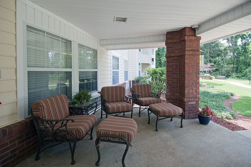 A cozy patio with striped cushioned chairs and ottomans next to a brick column.