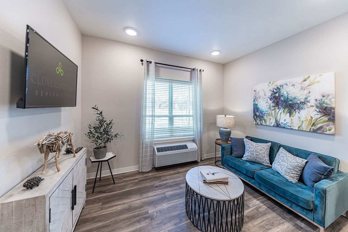 A modern living room with stylish decor, including a blue couch, coffee table, and wall art.