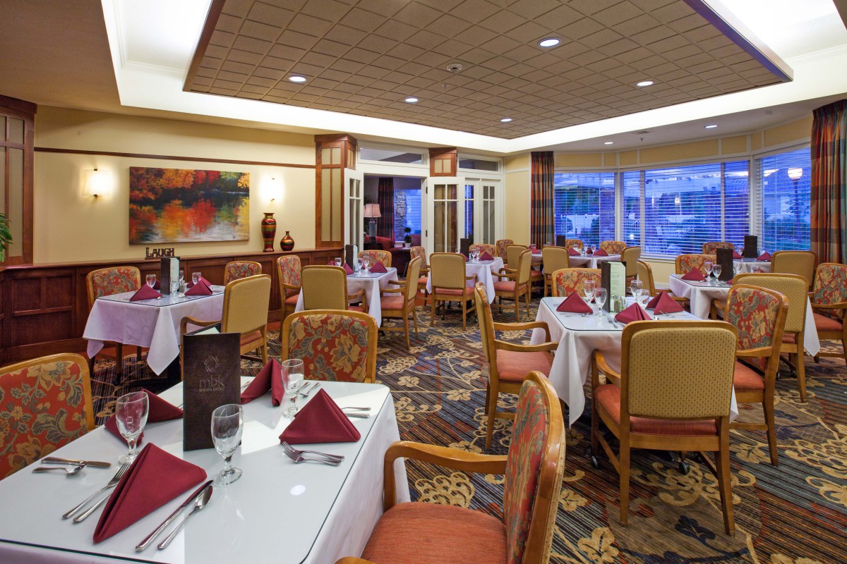 An elegant restaurant dining room with neatly arranged tables and chairs, decorated with stylish table settings.