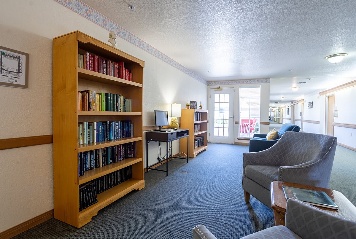 A cozy living room with bookshelves, comfortable seating, and a small desk area.