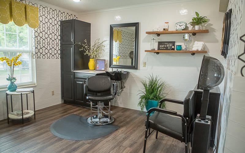 A modern and stylish hair salon interior with a barber chair, mirror, and decorative plants.