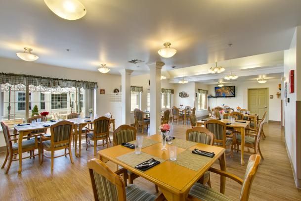 A spacious and well-lit dining area with multiple wooden tables and chairs arranged neatly.