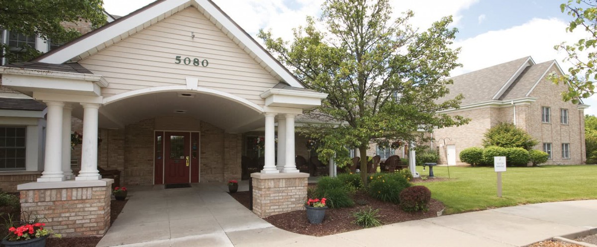 Entrance of a building with landscaped surroundings and columns.