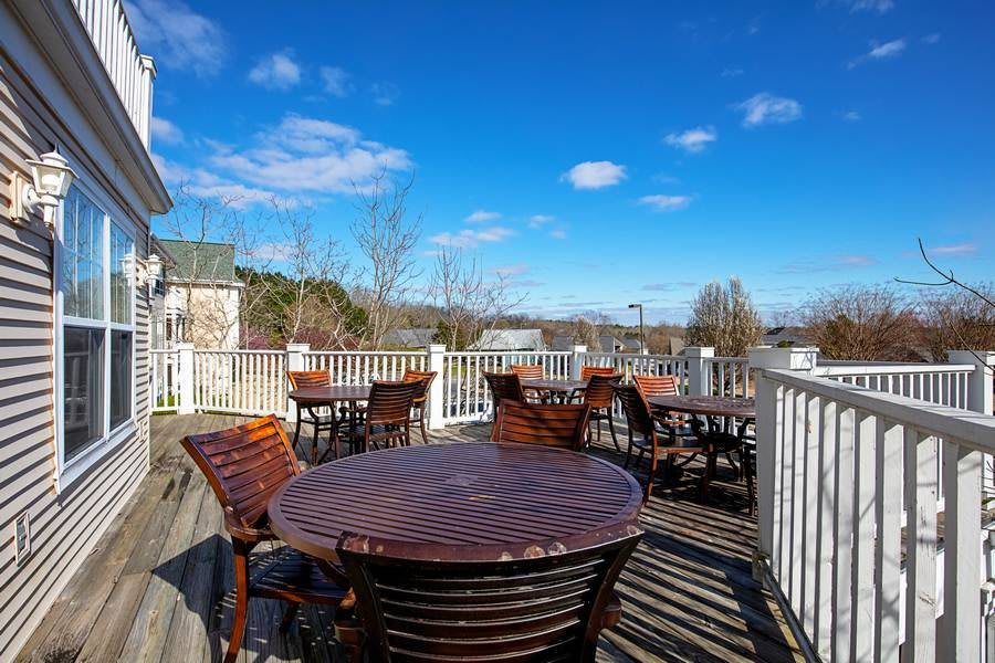 Outdoor patio with wooden tables and chairs under a clear blue sky.