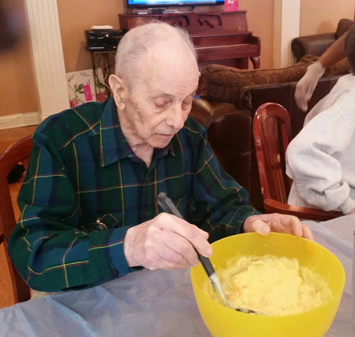 An elderly man enjoys preparing a meal in a cozy home setting.