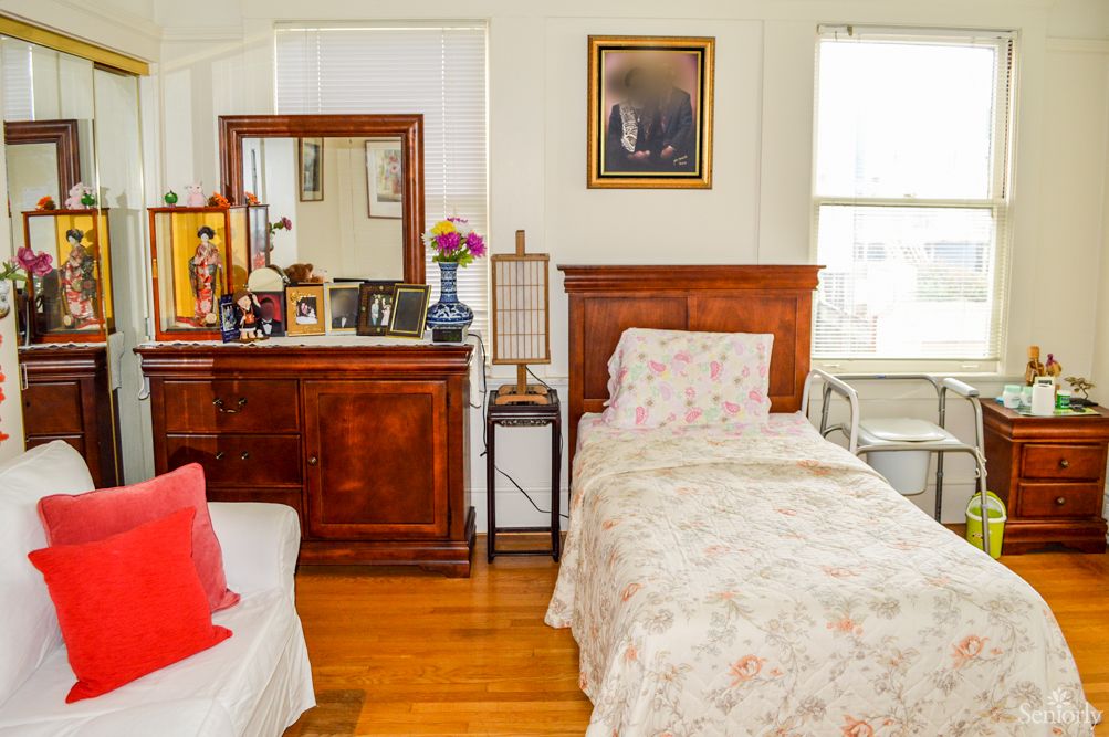 A cozy bedroom with a single bed and a dresser topped with photos and decor.
