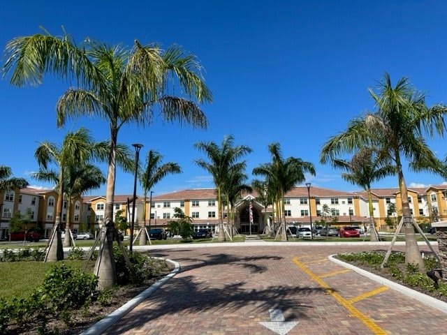 A sunny day at a residential complex with palm trees and a welcoming driveway.