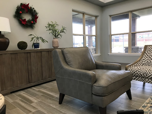A cozy living room featuring a stylish armchair, decorative plants, and natural light streaming through the windows.
