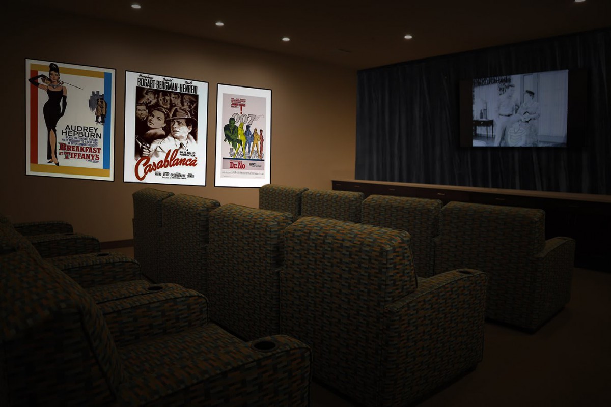 A cozy home theater with comfortable seating and illuminated movie posters on the wall.