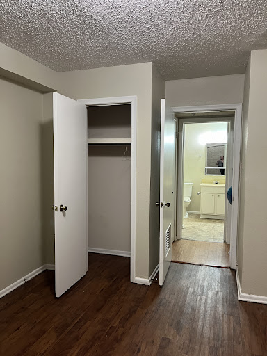 A view of a room featuring an open closet and two doors leading to different areas.