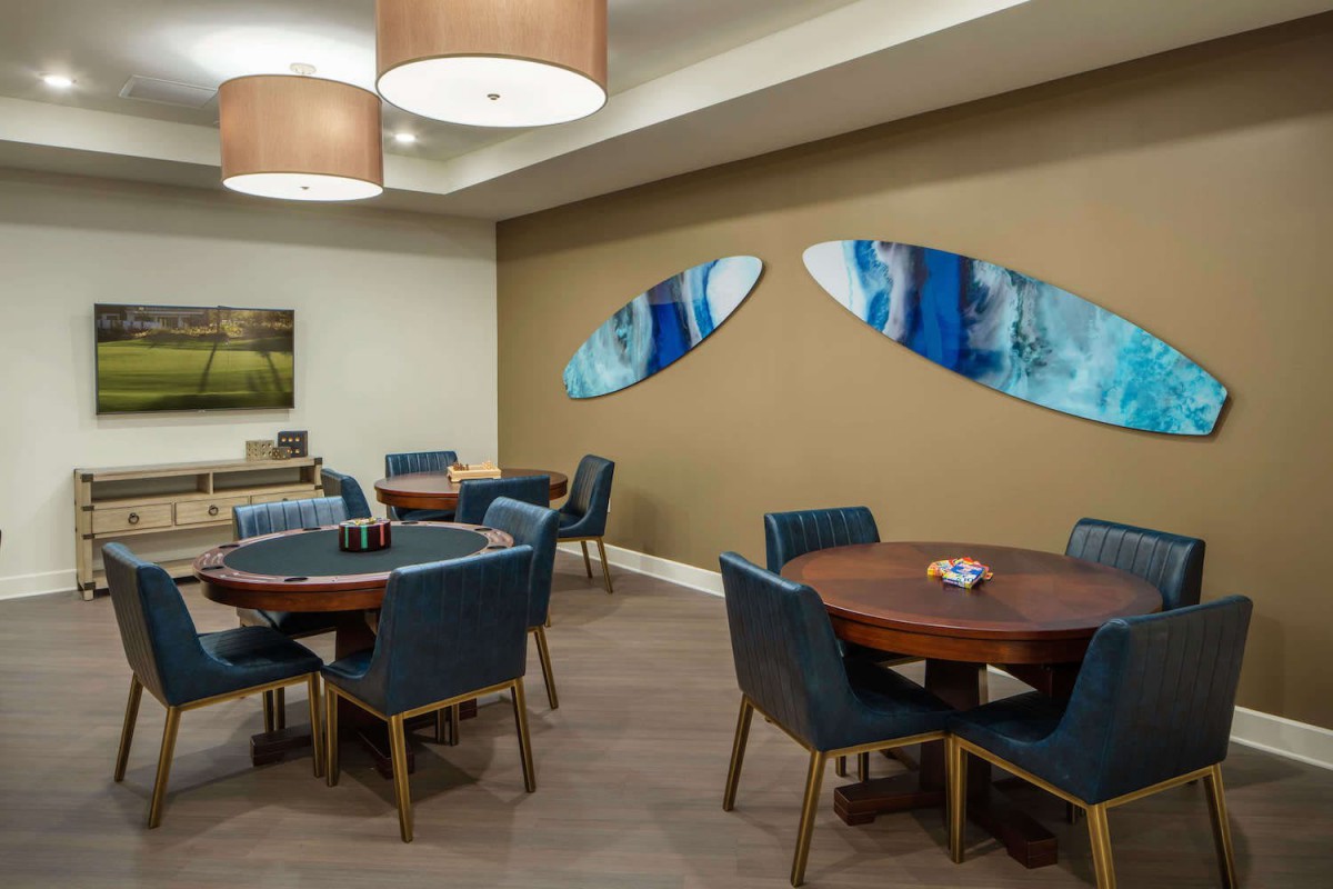 A modern dining area with round tables and blue upholstered chairs, featuring abstract artwork on the wall.